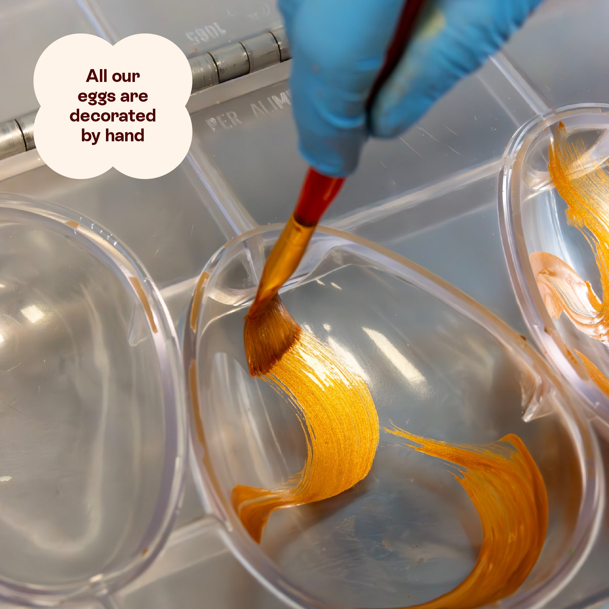 An Easter egg mould being hand-painted with golden cocoa butter