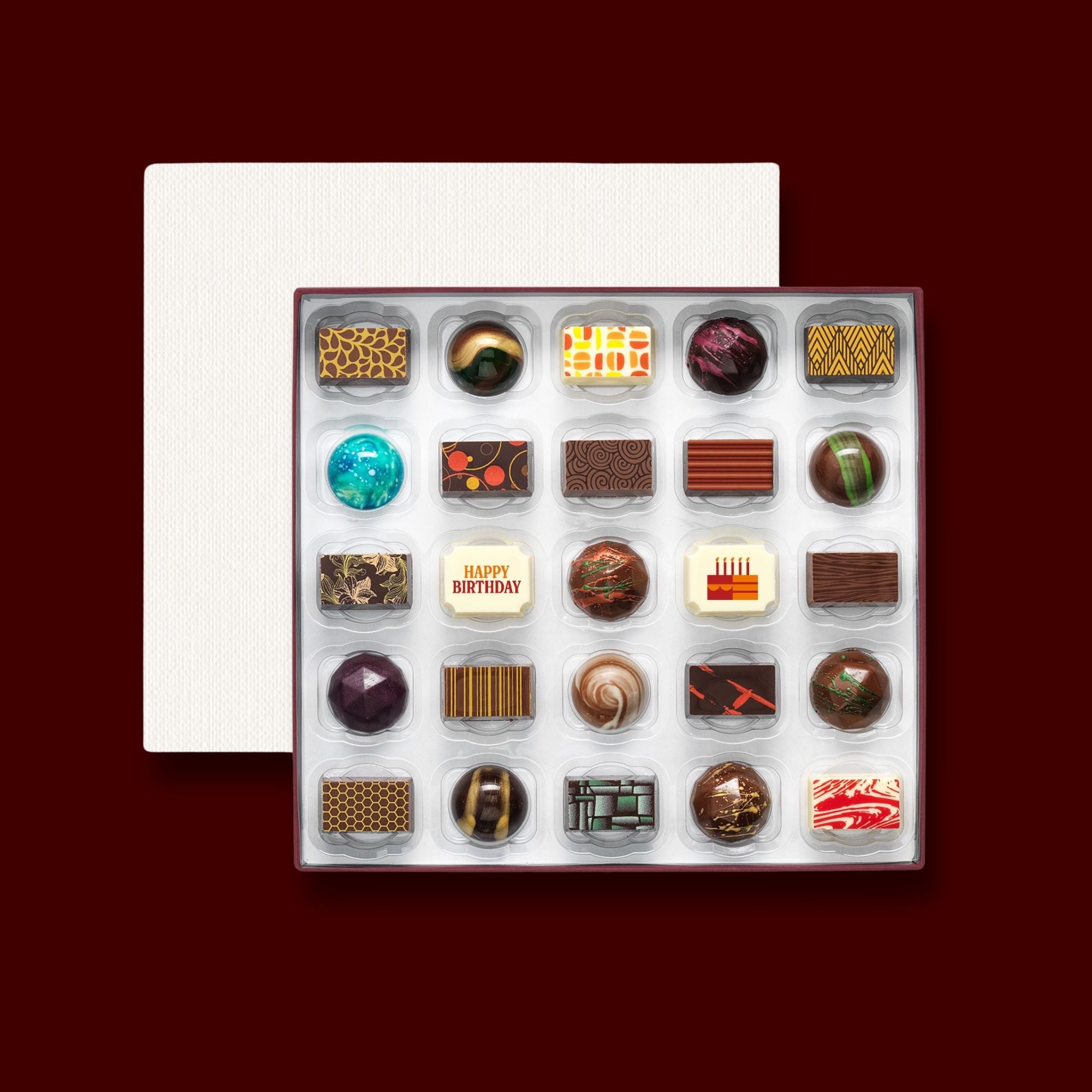 A box of 25 artisan chocolates colourfully decorated and featuring two Birthday themed designs