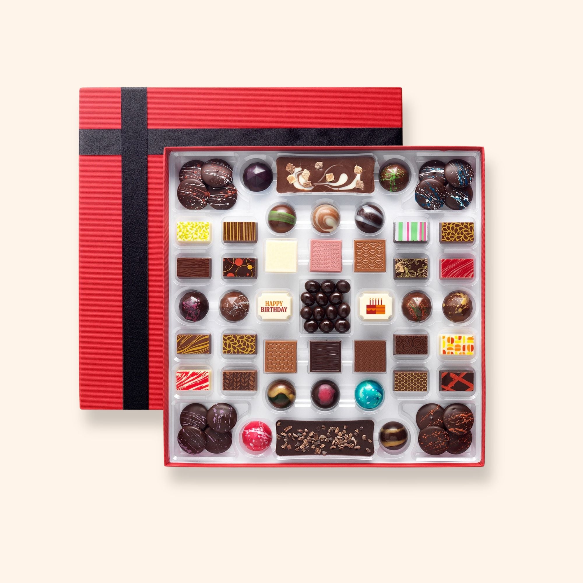 A chocolate box including buttons, bars, and coffee beans colourfully decorated and featuring two Birthday chocolates