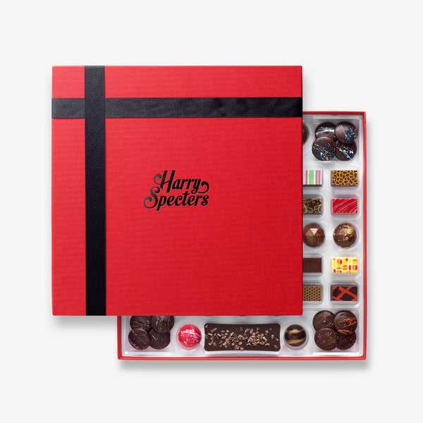 A box of 45 artisan chocolates featuring Eid Mubarak themed designs as well as mini chocolate bars, hot chocolate buttons, and chocolate covered coffee beans partially covered by a box lid featuring the name Harry Specters