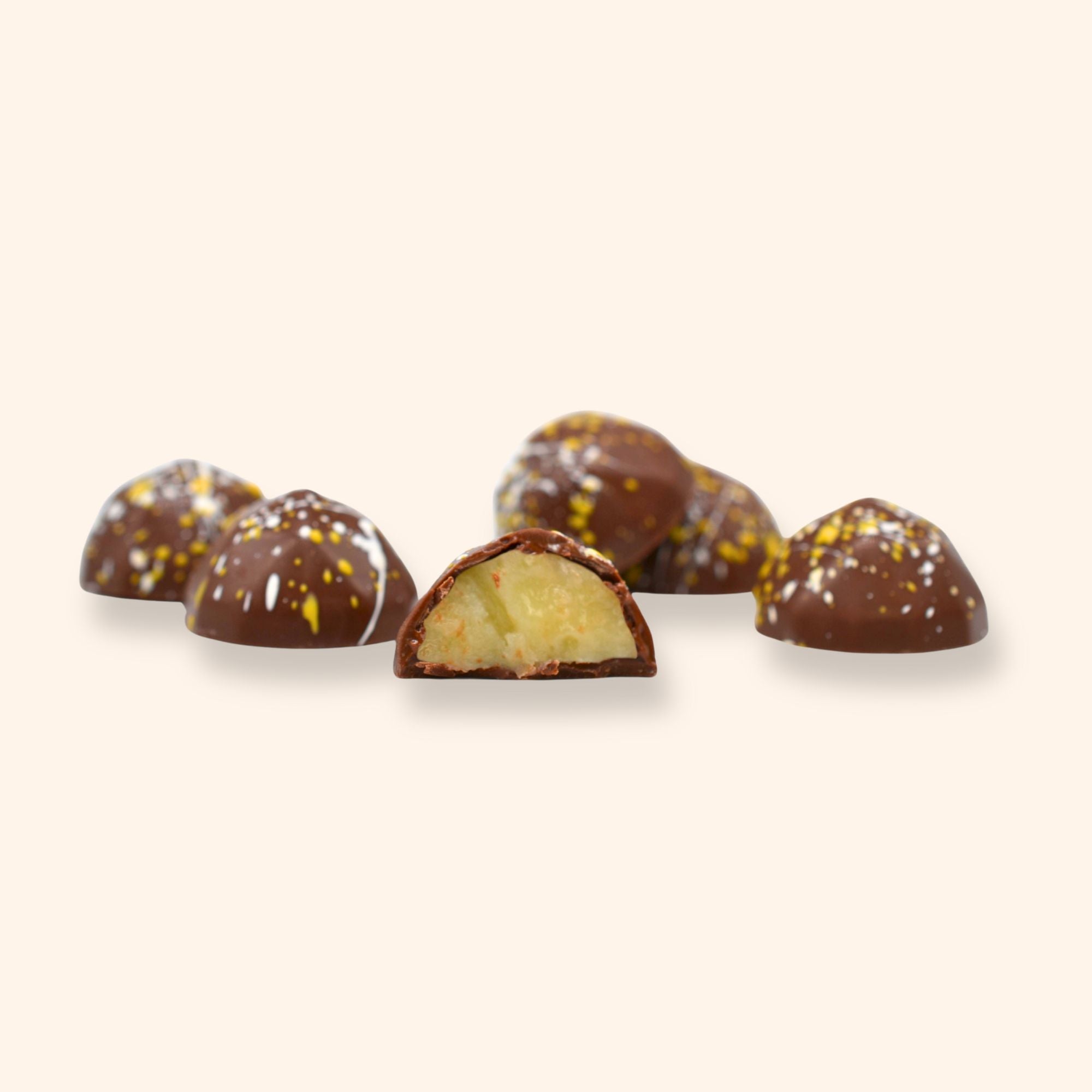 Pina Colada chocolates with one cut open to reveal a creamy filling on a beige background