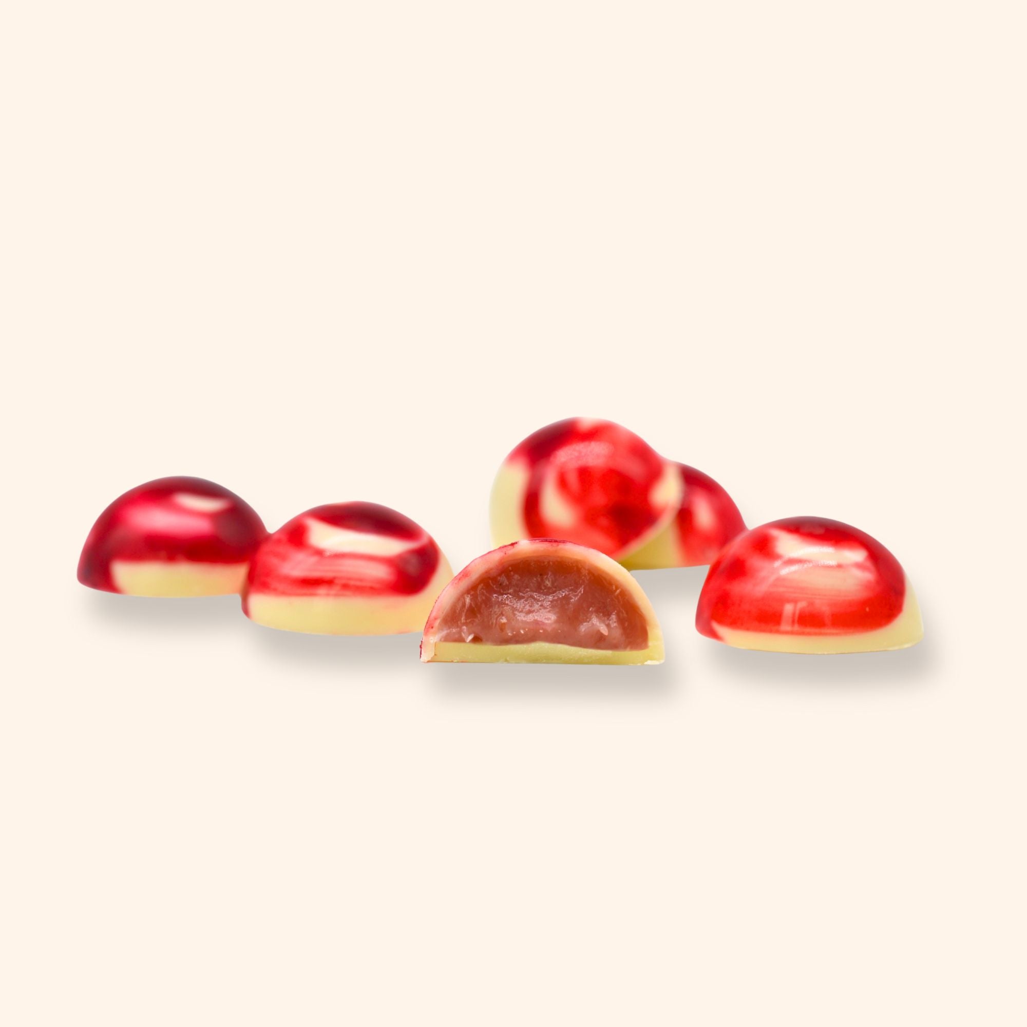 Red and white strawberry cream chocolates on a light beige background