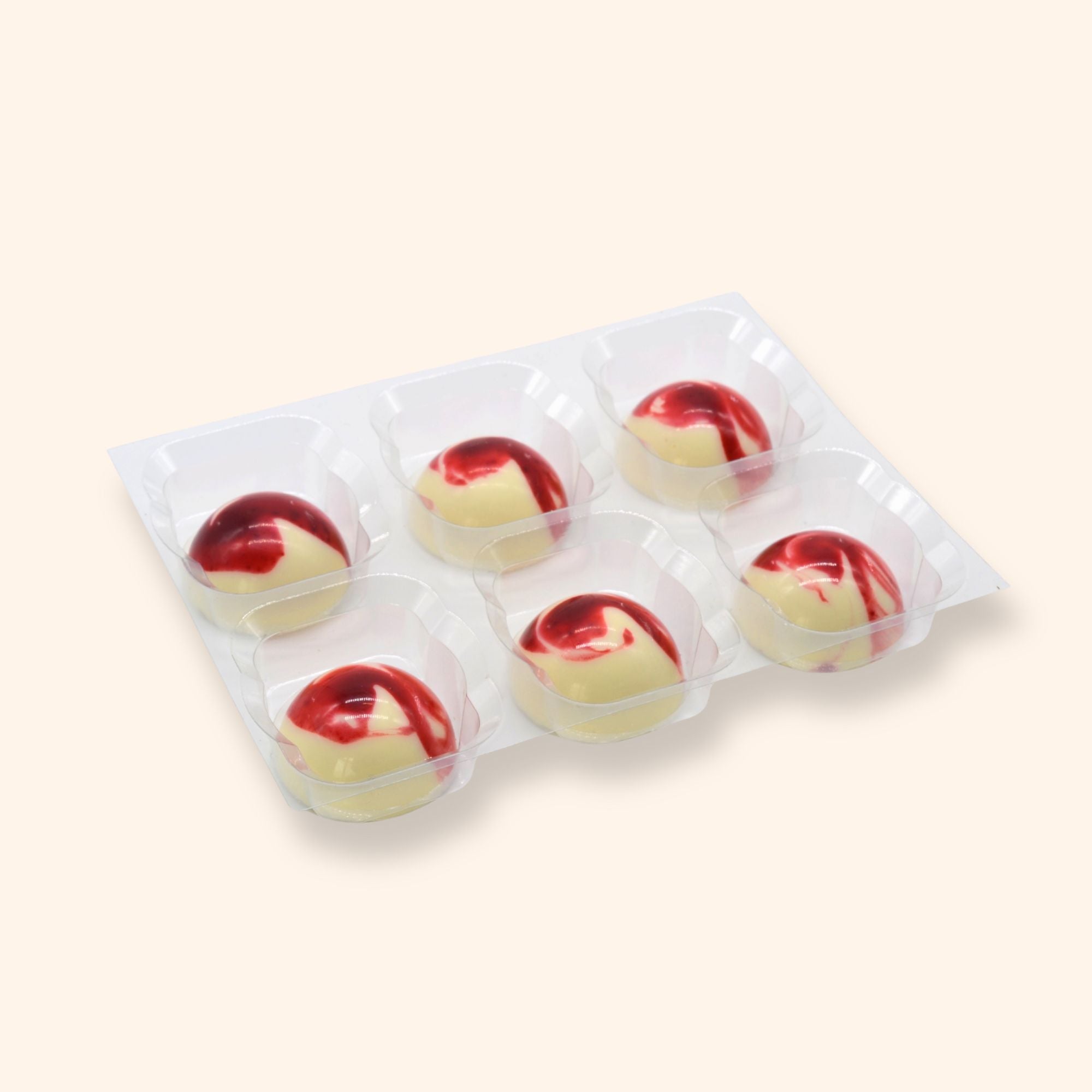 Packaged strawberry cream chocolates with red and white design on a beige background