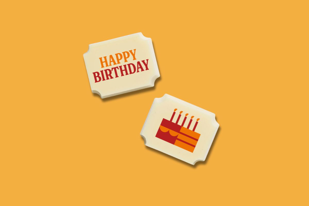 Two luxury white chocolates with a 'happy birthday' message on an orange background