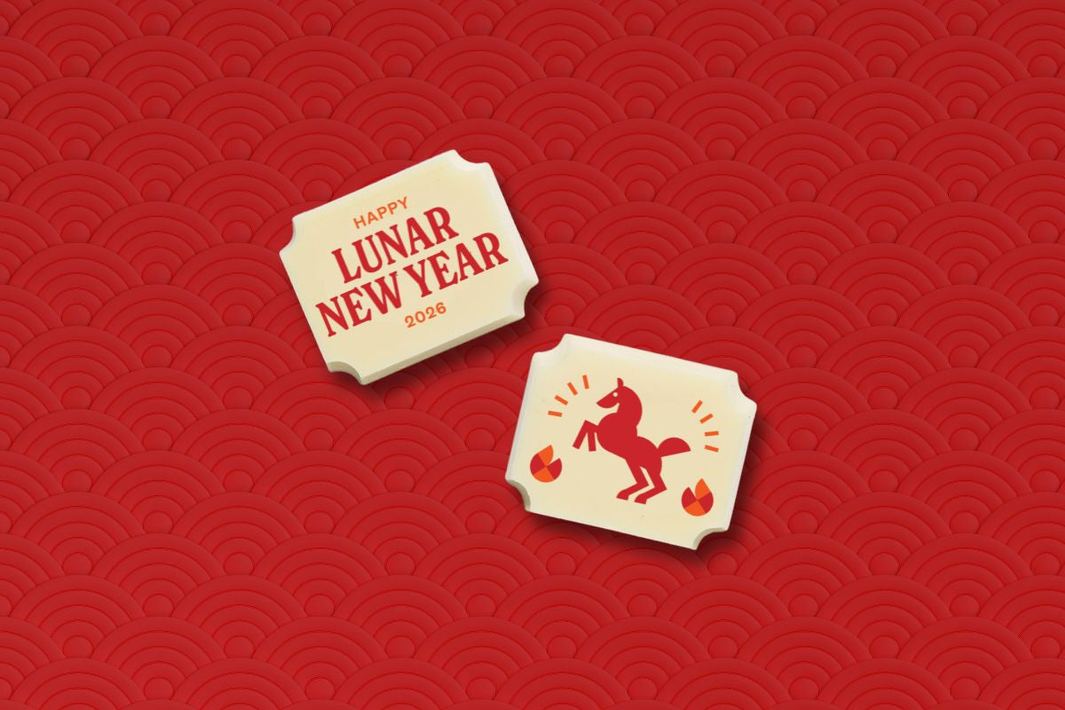 Two white chocolates with 'Happy Lunar New Year 2023' text and a horse illustration on a red patterned background.