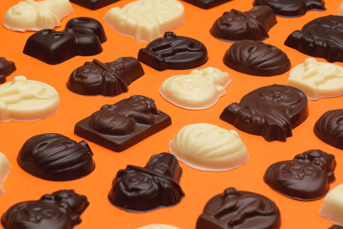 A selection of chocolate Halloween shapes in milk dark and white on an orange background