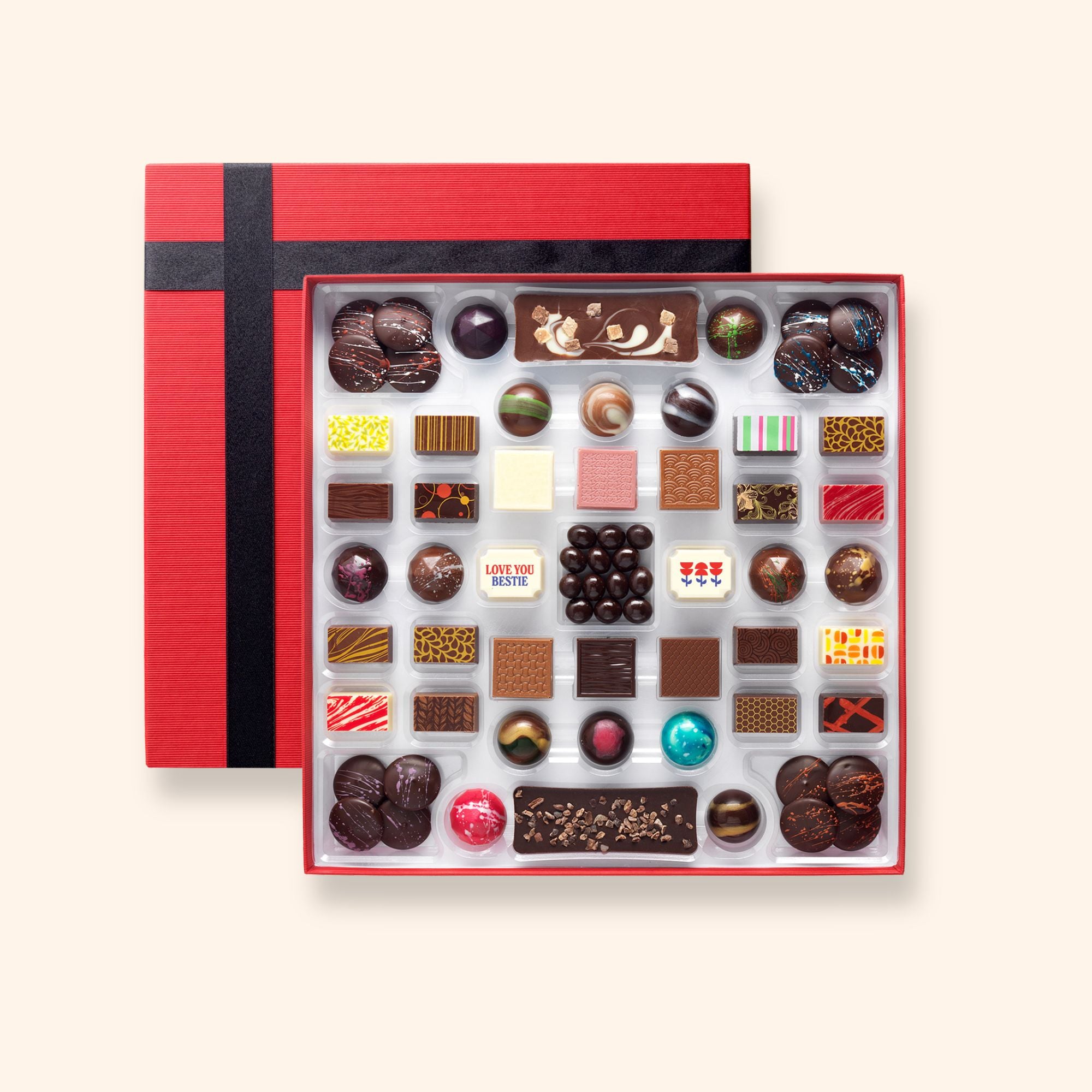 Assorted artisan chocolates with a 'love you bestie' message in a red box on a white background