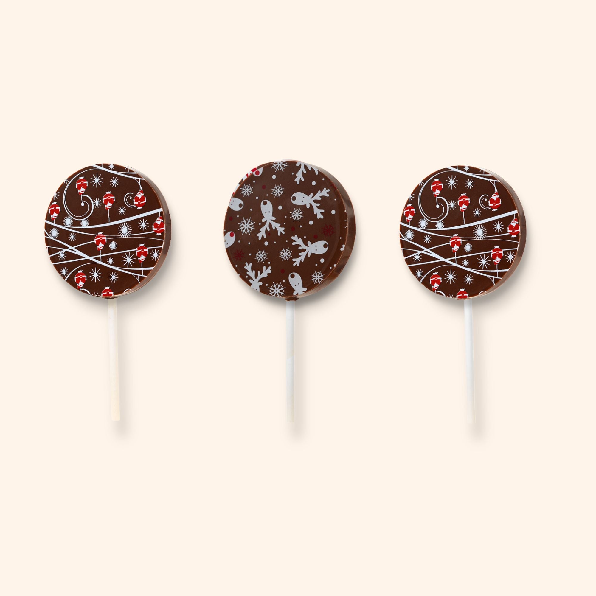 Three dark chocolate lollipops with Christmas patterns on a beige background
