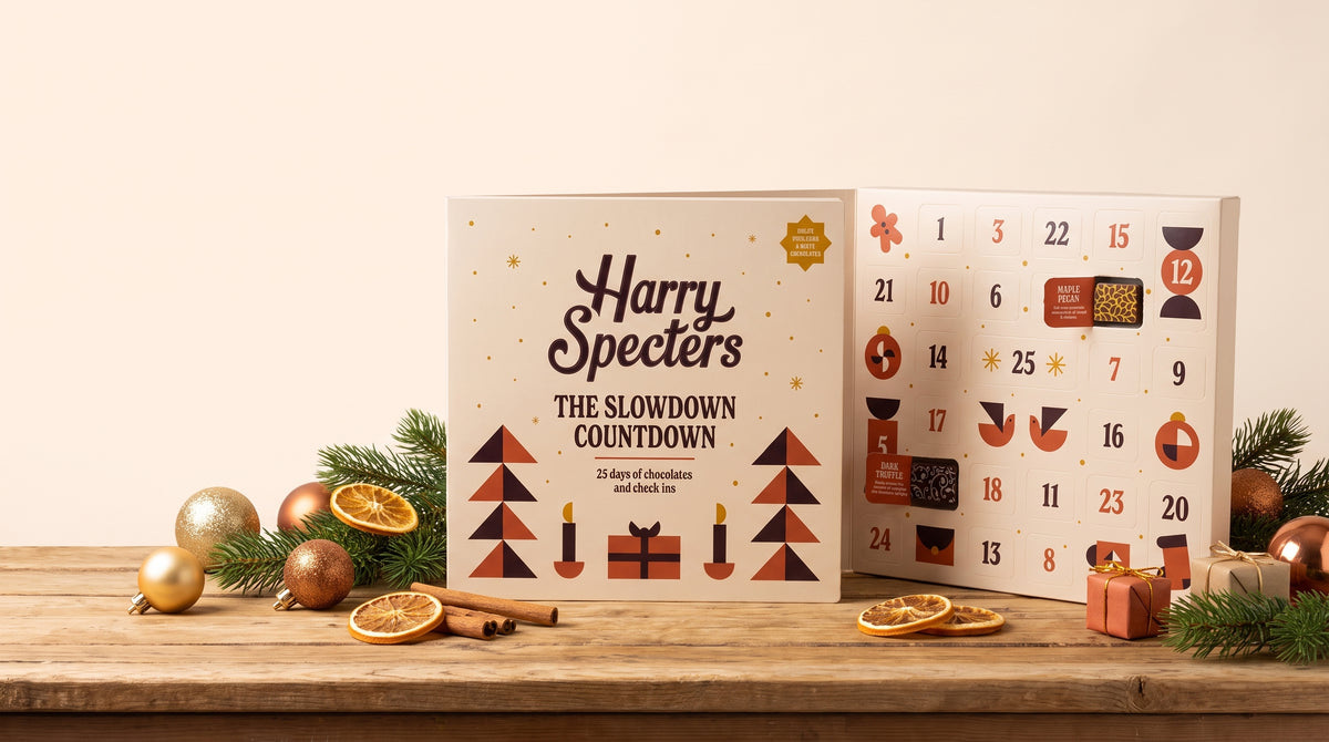 Christmas chocolate boxes with their lids off, the Christmas-printed chocolates visible inside, on a yellow background