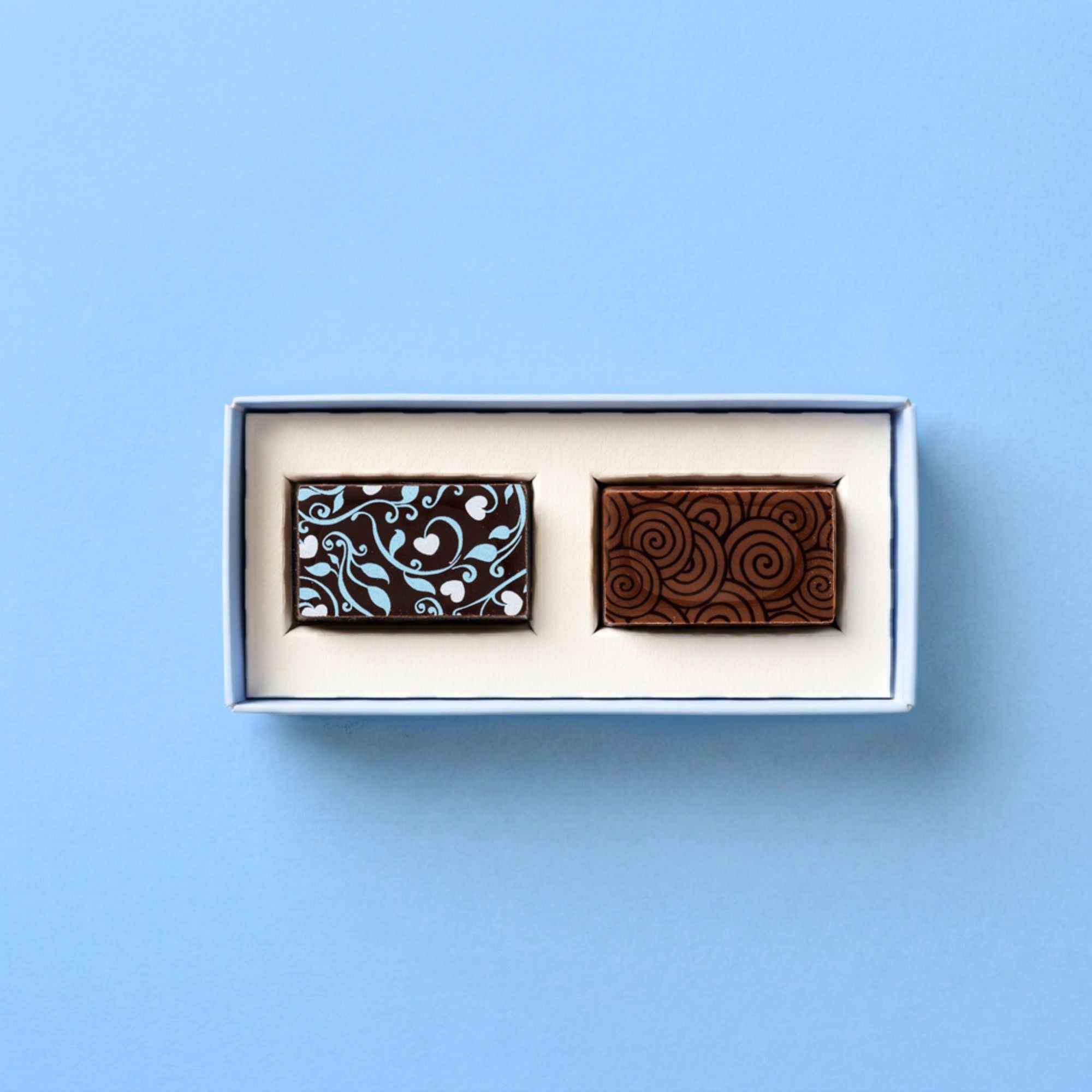 Two premium chocolates in a box on a light blue background