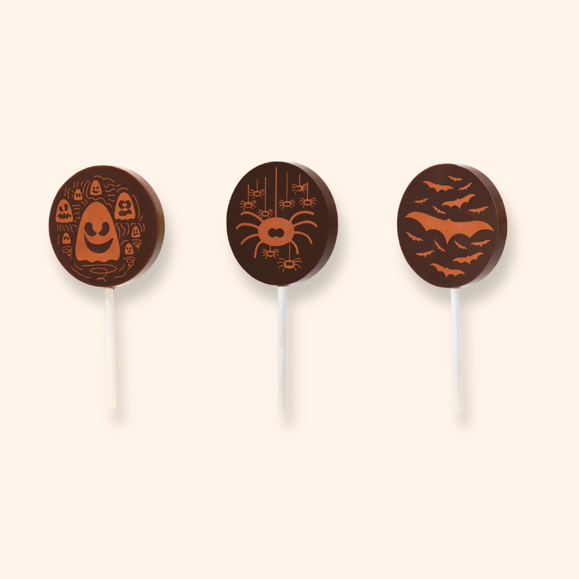 Three Halloween-themed milk chocolate lollipops on a white background