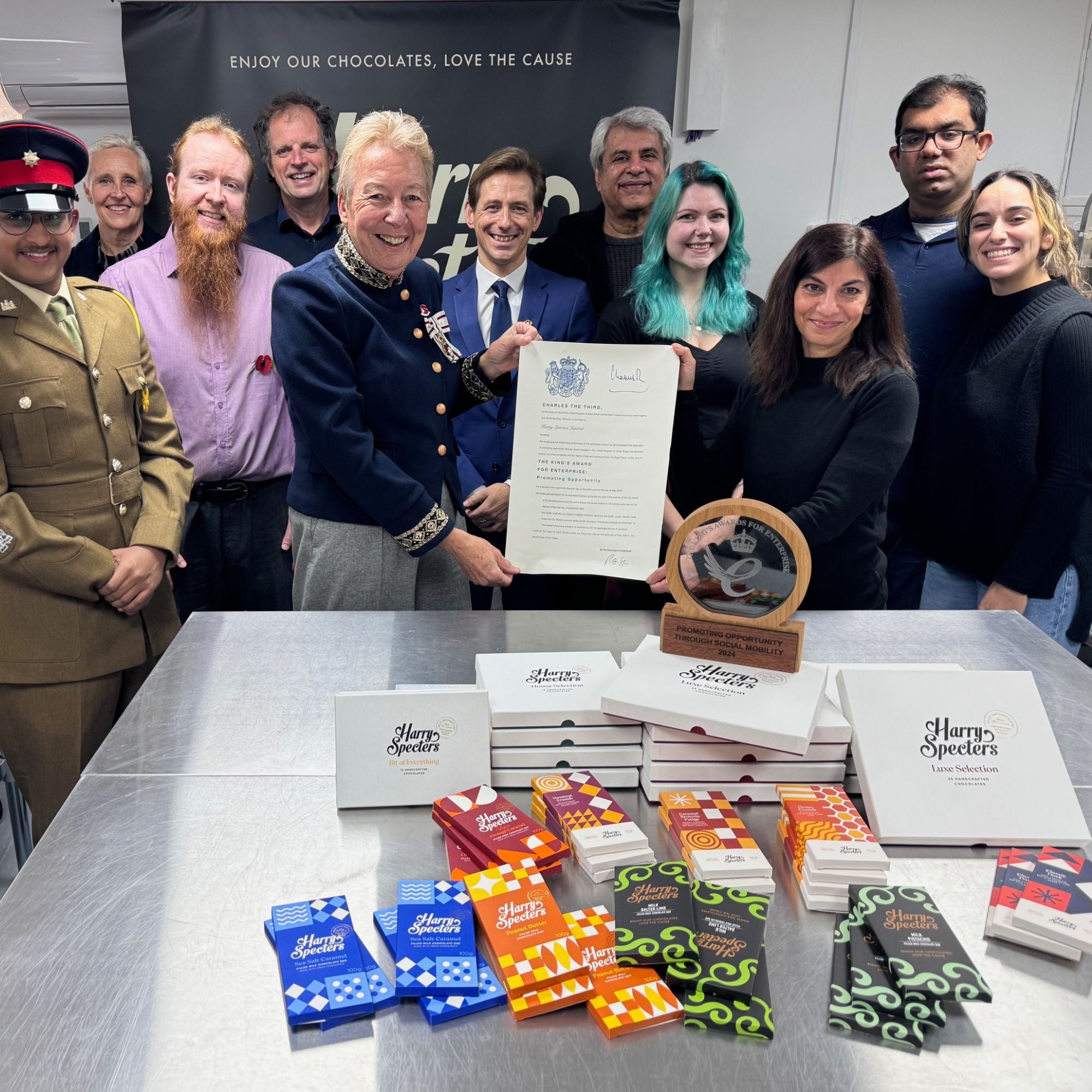 Team Harry Specters holding the Kings Award certificate, surrounded by chocolate boxes and bars on a table.