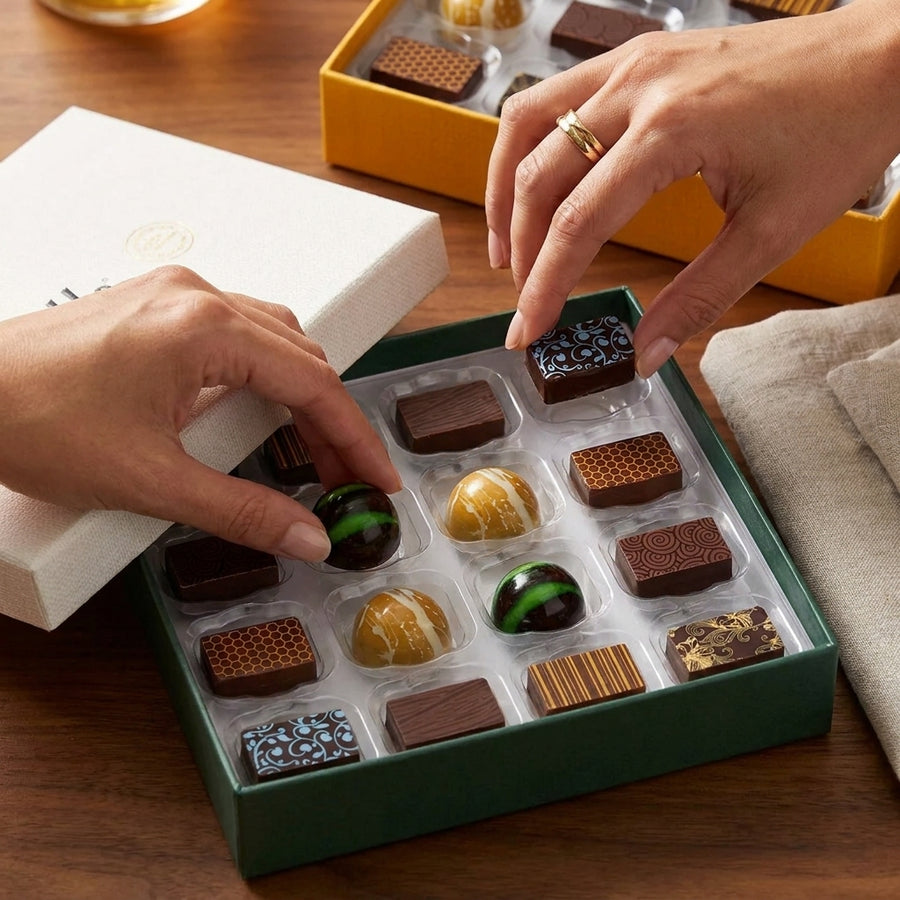 Two people picking up chocolates from the House Selection Sharing box