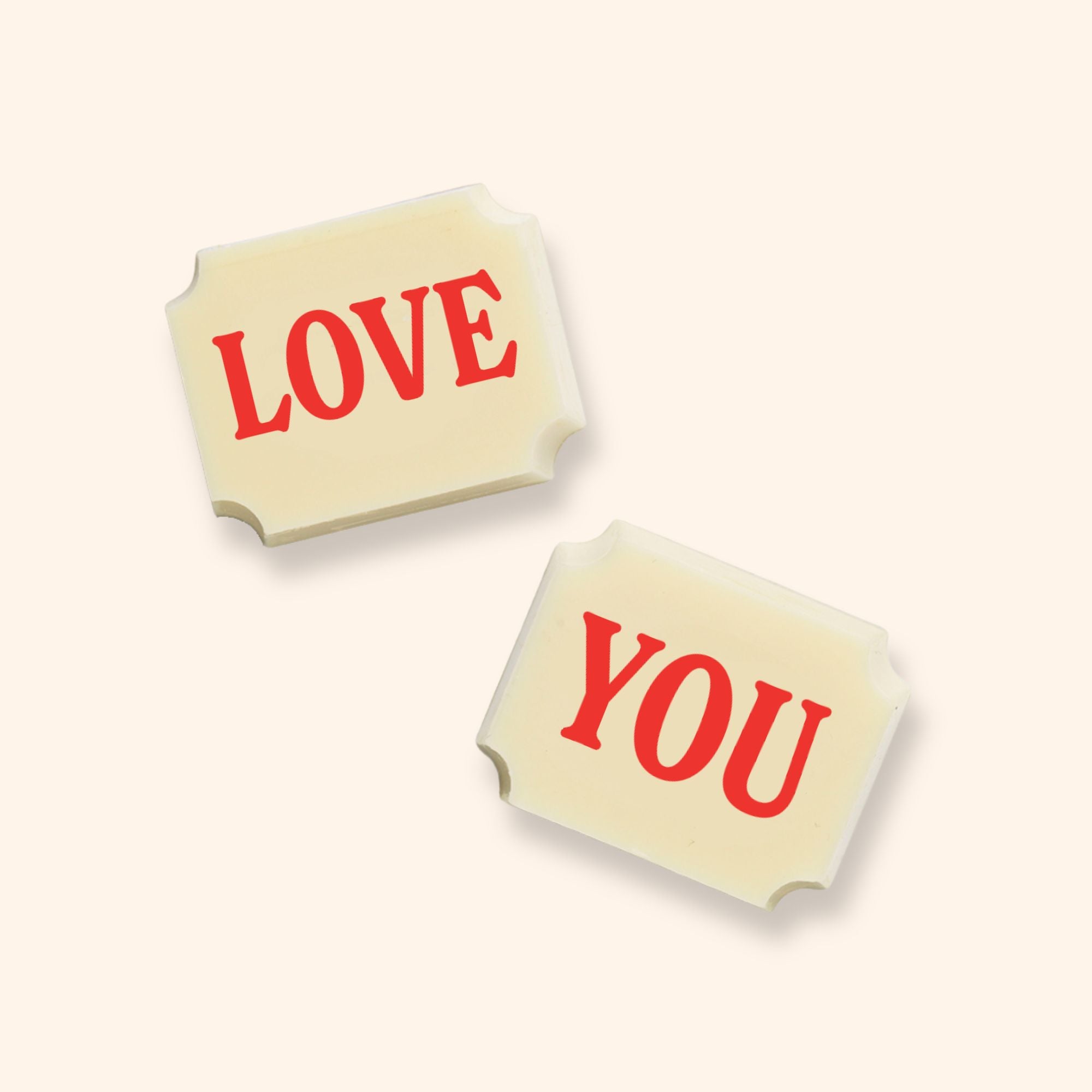 Two white rectangular chocolates with red text 'LOVE' and 'YOU' on a pale background