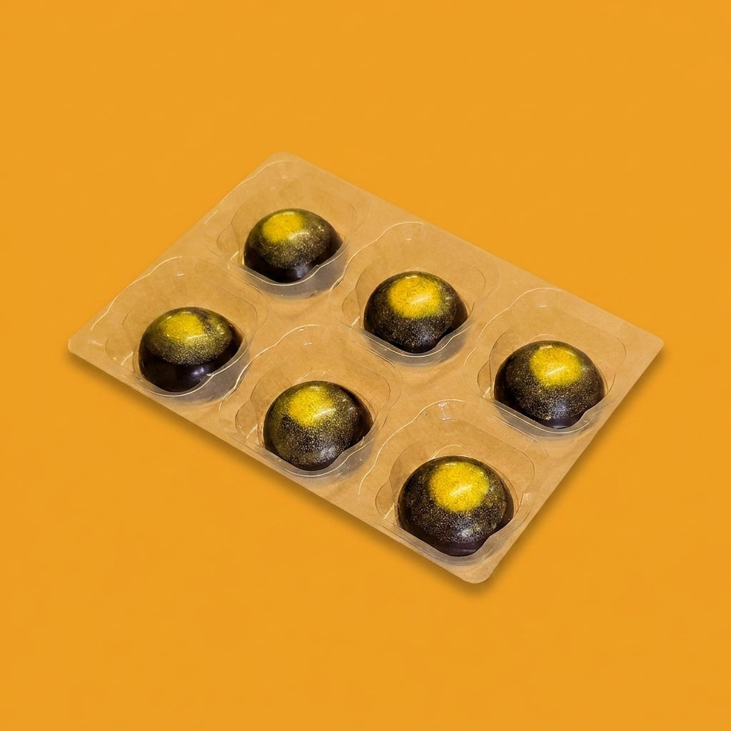 Six mango calamansi dark chocolates in a tray, decorated with a gold pattern