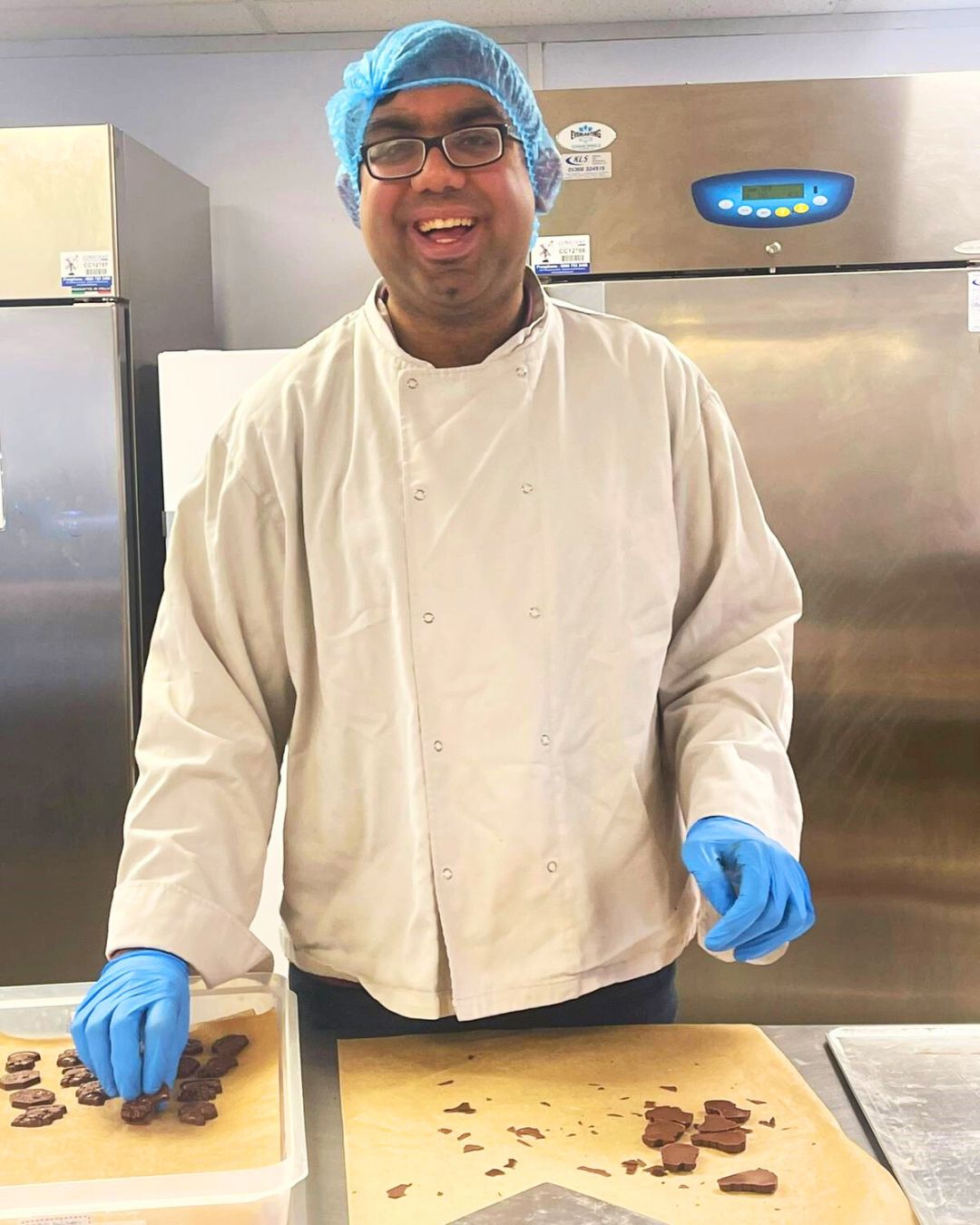 An autistic employee smiling while quality checking chocolate shapes