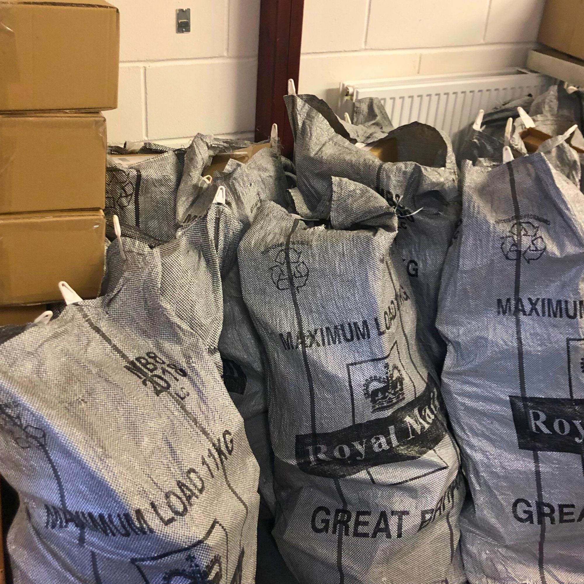 A collection of cardboard boxes and Royal mail post bags filled with chocolate orders.