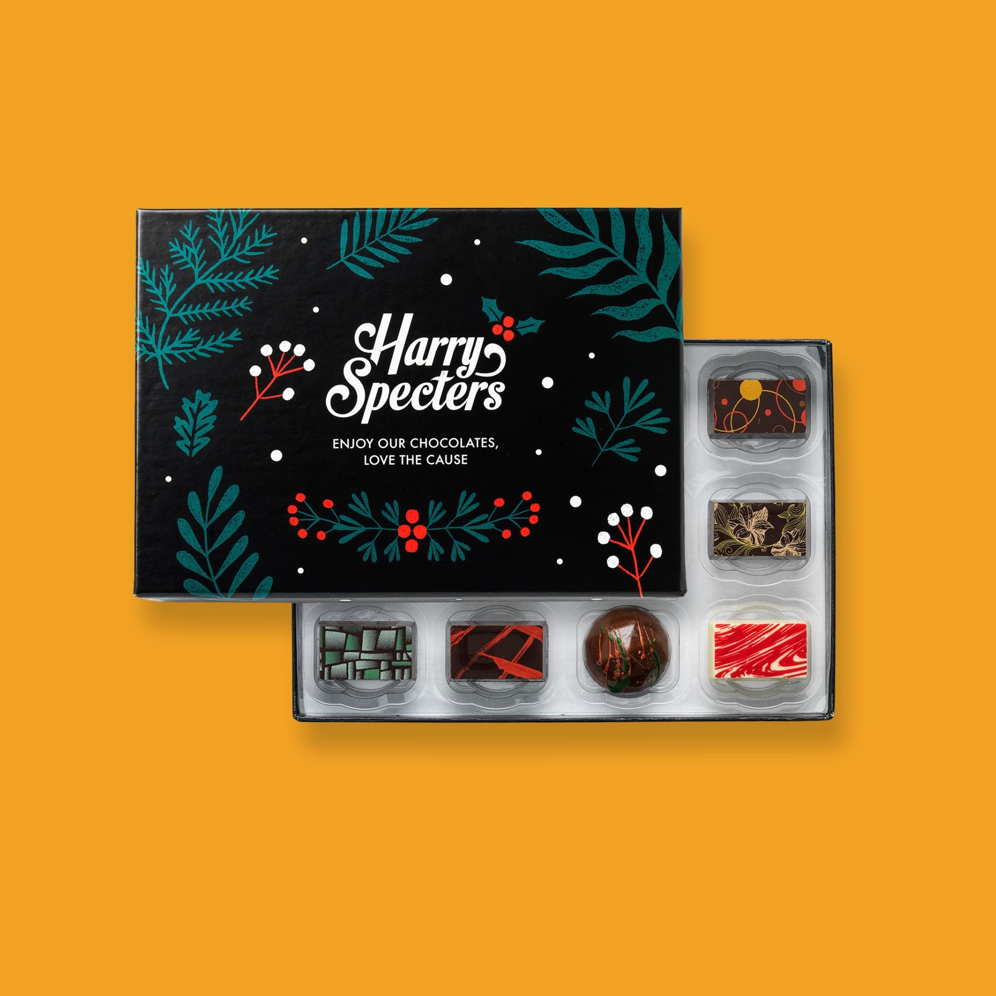 A box of 12 artisan chocolates by Harry Specters including Christmas themed designs partially covered by a festive box lid 