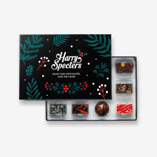 A box of 12 artisan chocolates by Harry Specters including Christmas themed designs partially covered by a festive box lid 