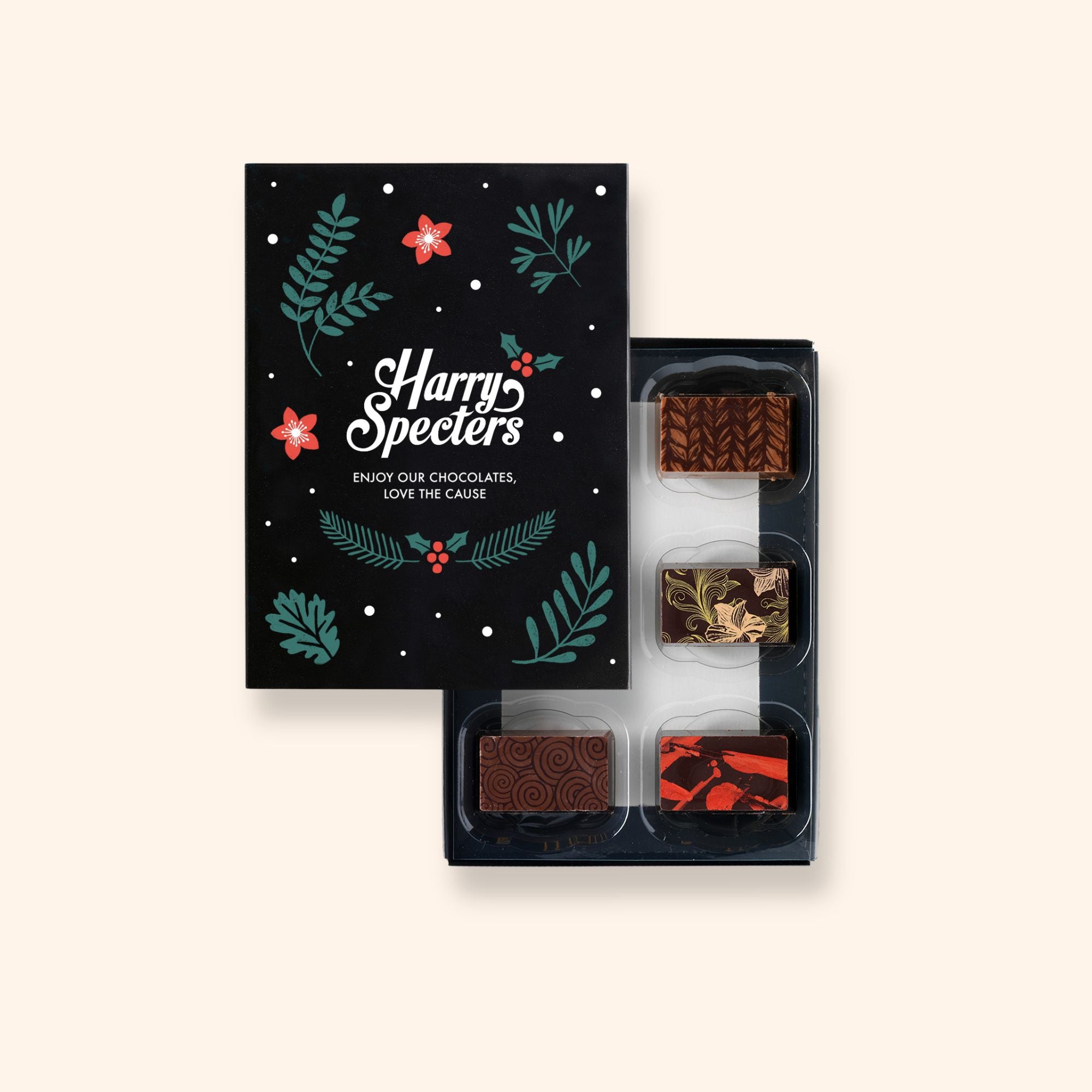 A box of 6 artisan chocolates by Harry Specters including a Christmas themed chocolate partially covered by a box lid 
