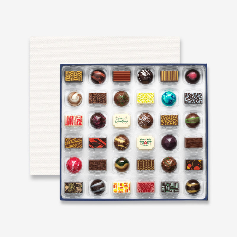 A box of 36 artisan chocolates colourfully decorated and featuring two Christmas themed designs