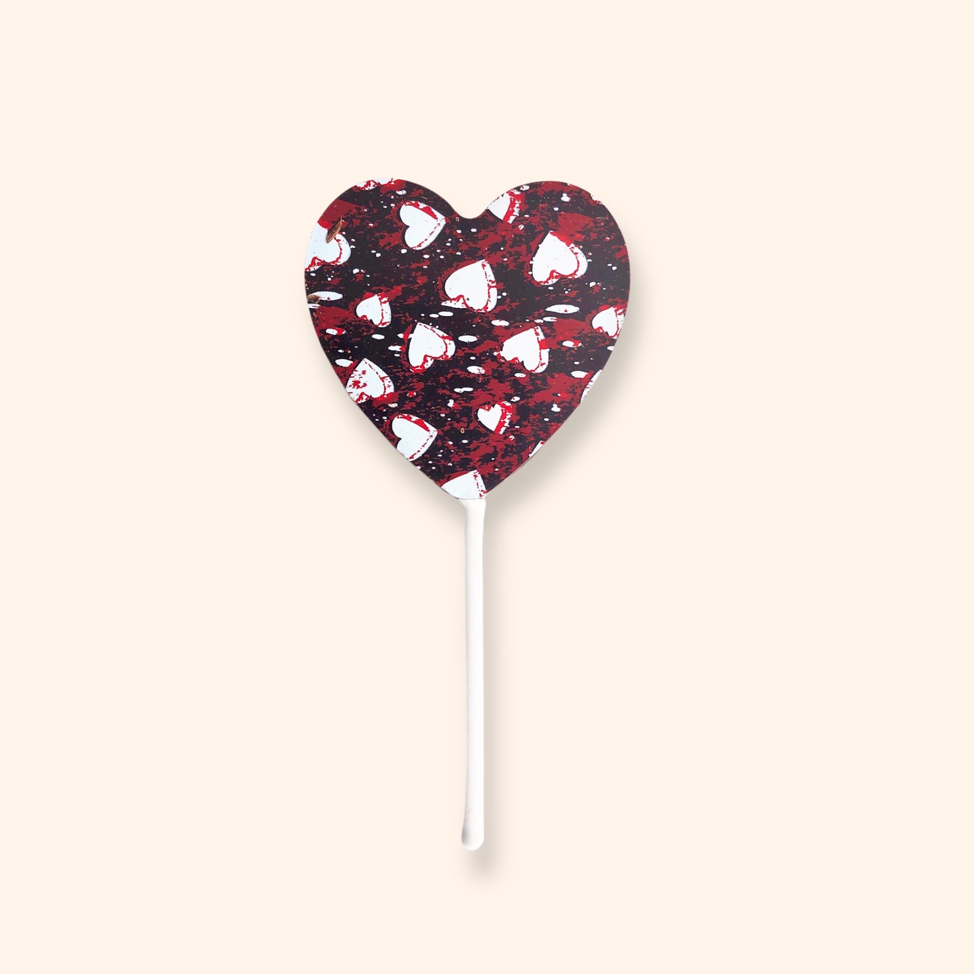 A heart shaped dark chocolate lollipop featuring a white and red heart design
