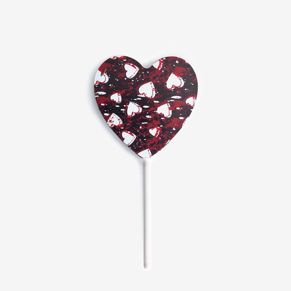 A heart shaped dark chocolate lollipop featuring a white and red heart design