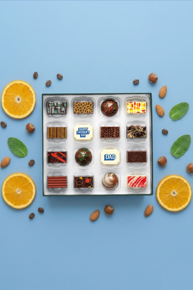 Luxury Father's Day chocolates in a box with oranges and mint leaves on a blue background
