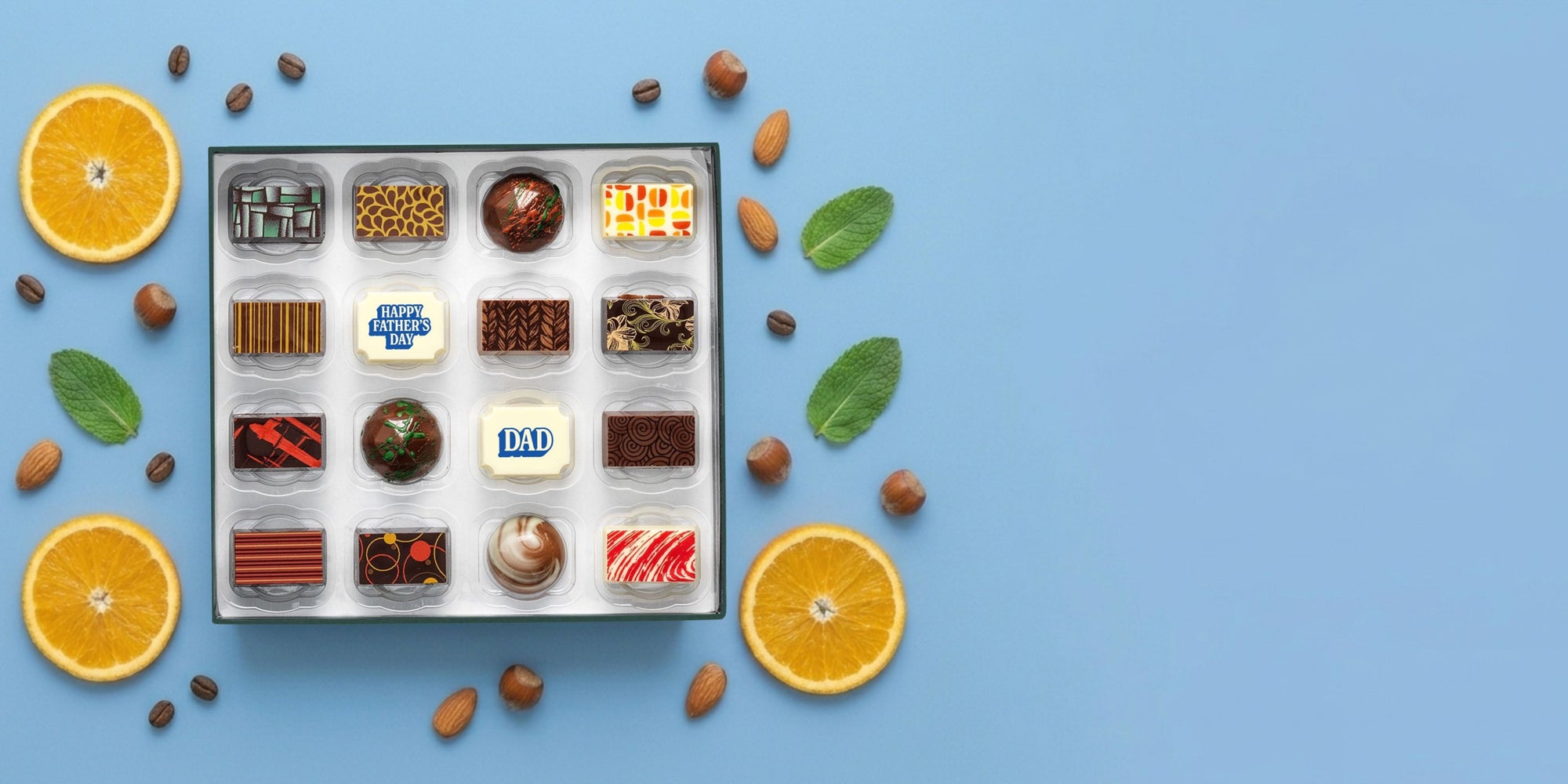 Luxury Father's Day chocolates in a box with oranges and mint leaves on a blue background