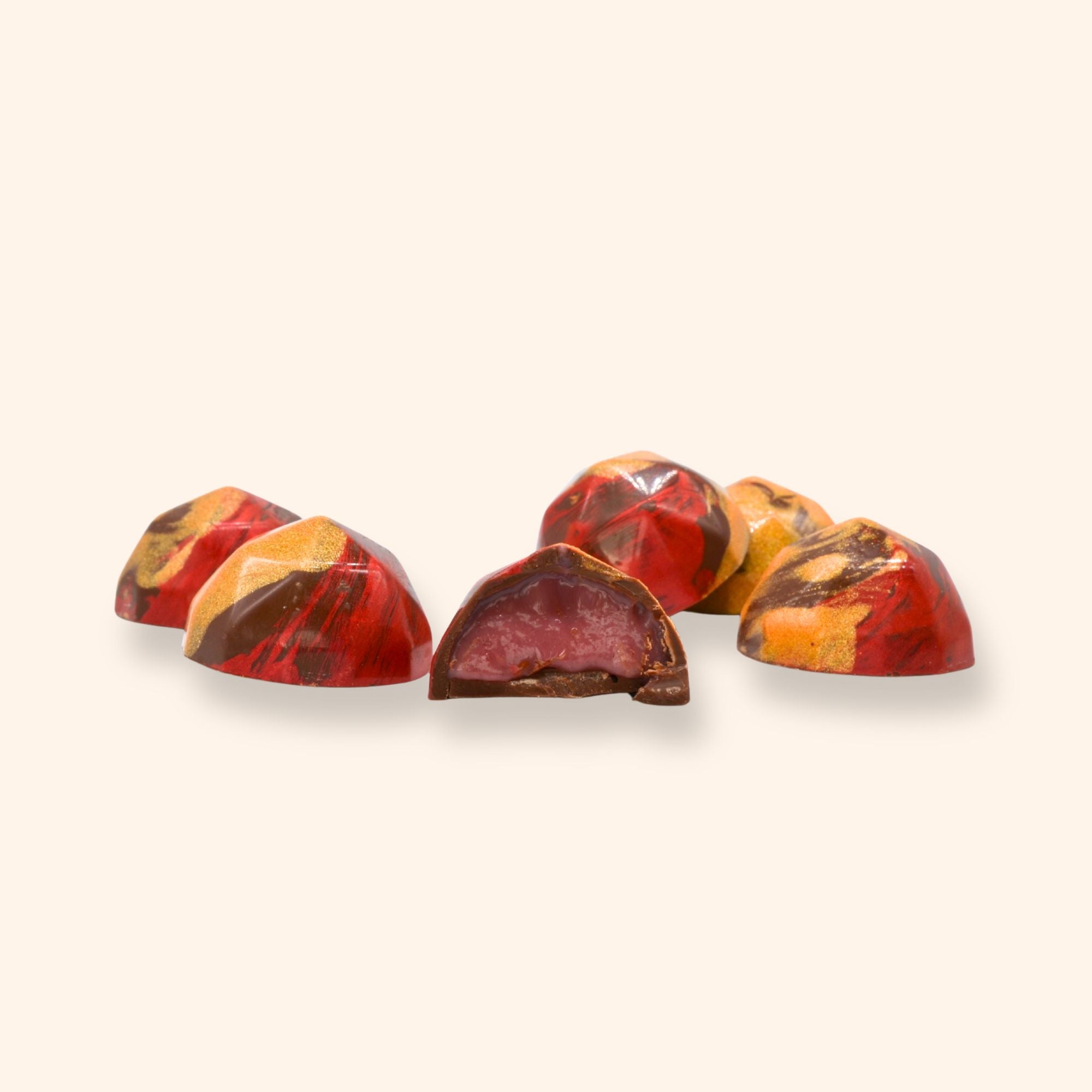 Five marbled raspberry rose chocolate pieces on a beige background