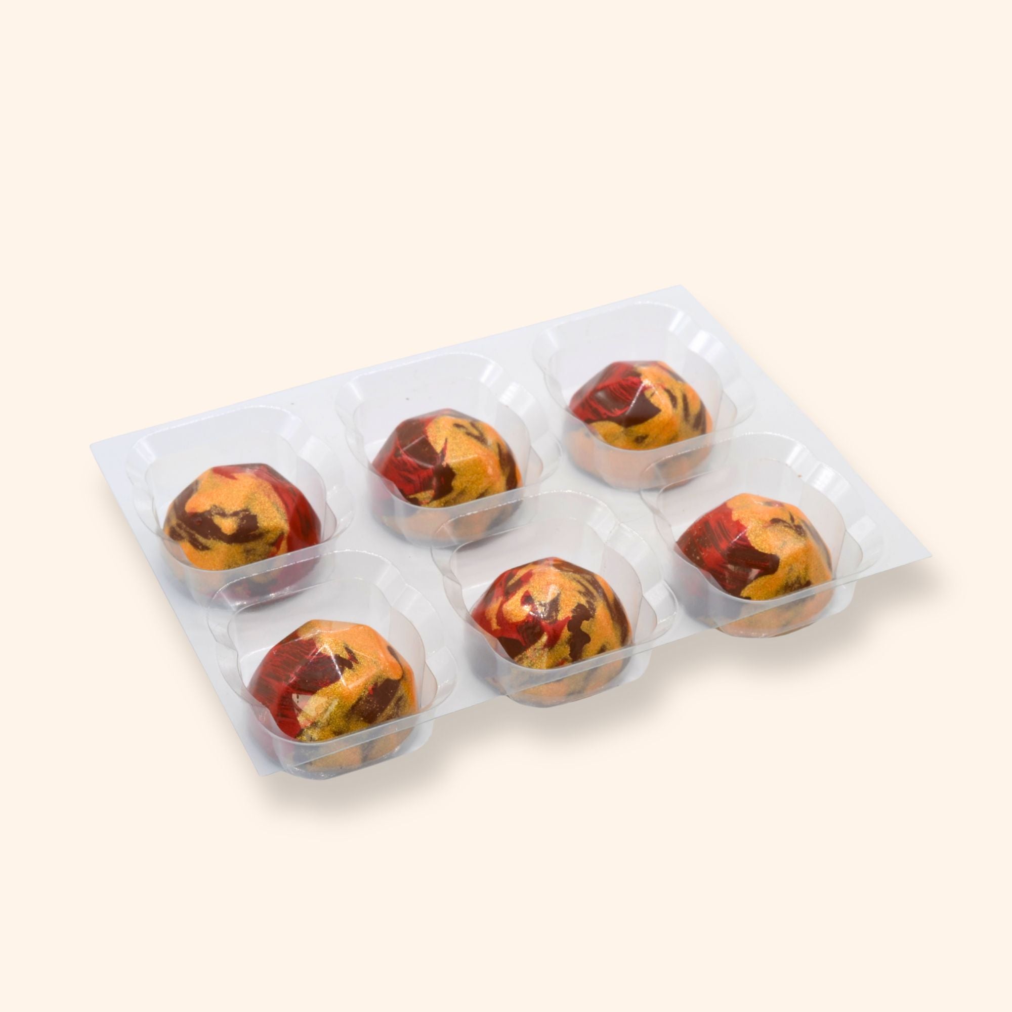 Pack of six raspberry rose chocolates in a plastic tray on a beige background