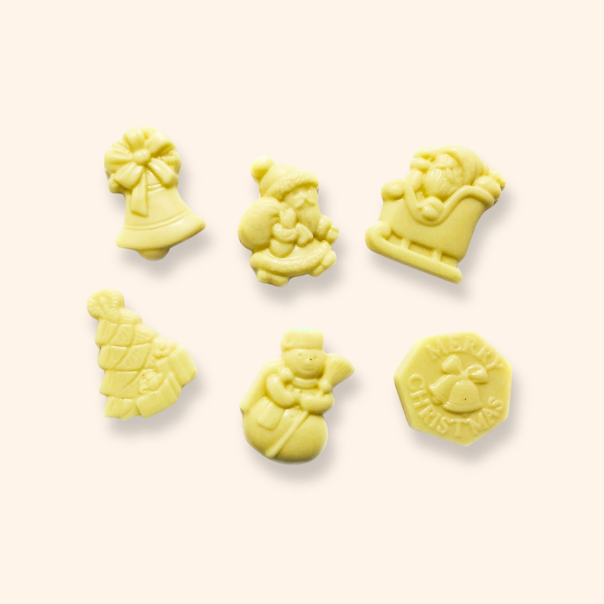 A group of white chocolate Christmas shapes including snowmen, a Christmas tree, and Santa Claus
