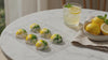 Lemon elderflower chocolates in a tray with a glass of lemonade and bowl of lemons