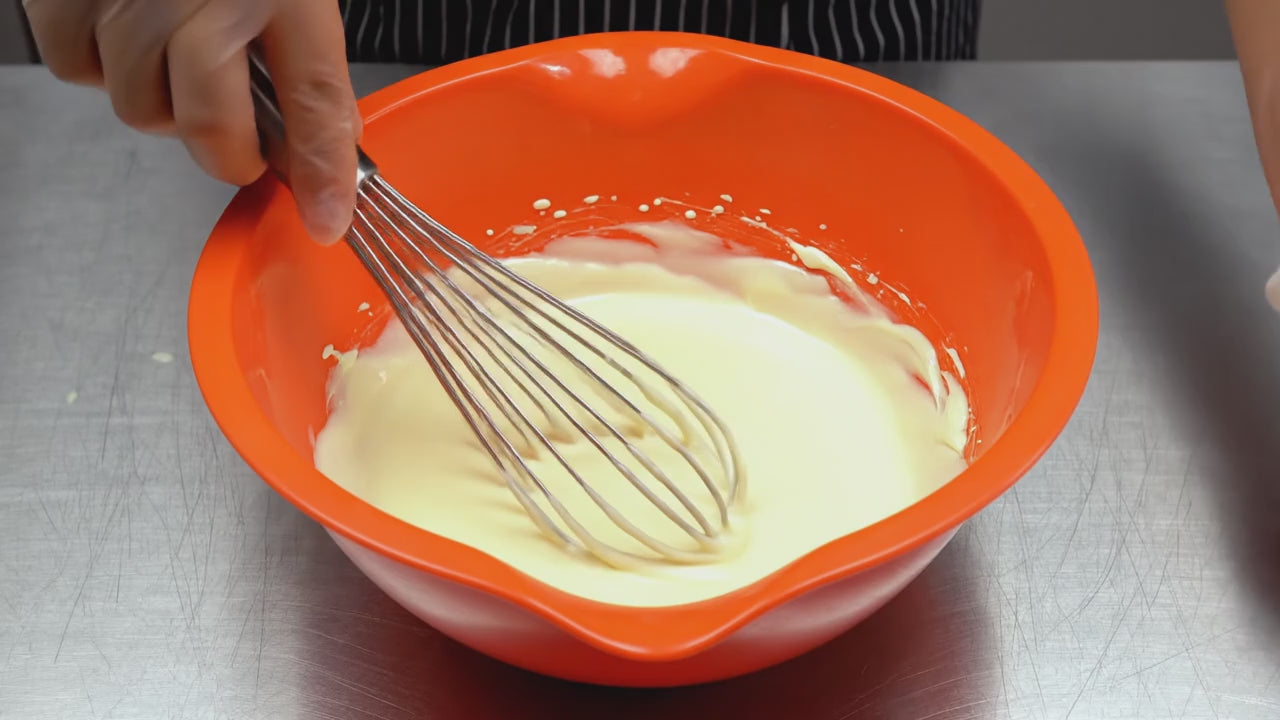 Pina colada ganache being mixed in an orange bowl