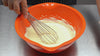 Pina colada ganache being mixed in an orange bowl