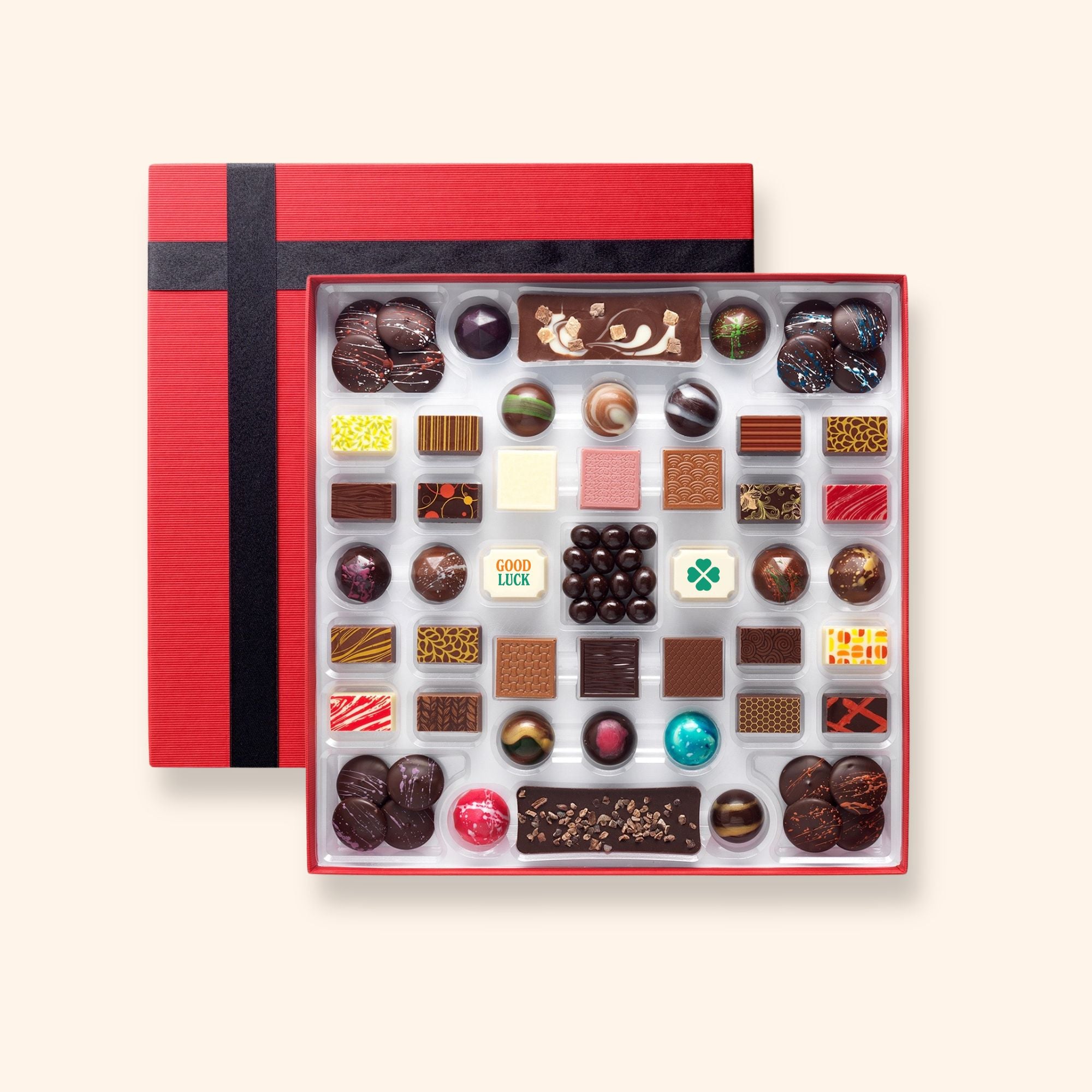 A chocolate box including buttons, bars, and coffee beans colourfully decorated and featuring two good luck chocolates