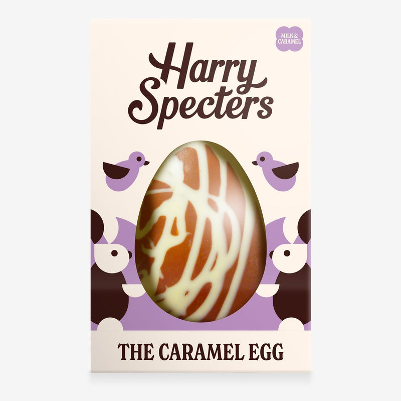 A caramel chocolate Easter egg decorated with a white chocolate swirl in a colourful box with an Easter bunny design