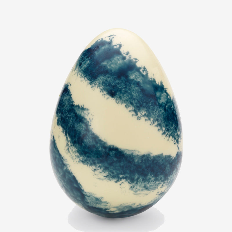 A white chocolate Easter egg decorated with blue stripes