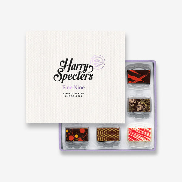 A box of 9 artisan chocolates by Harry Specters including Valentine's Day themed designs partially covered by a box lid 