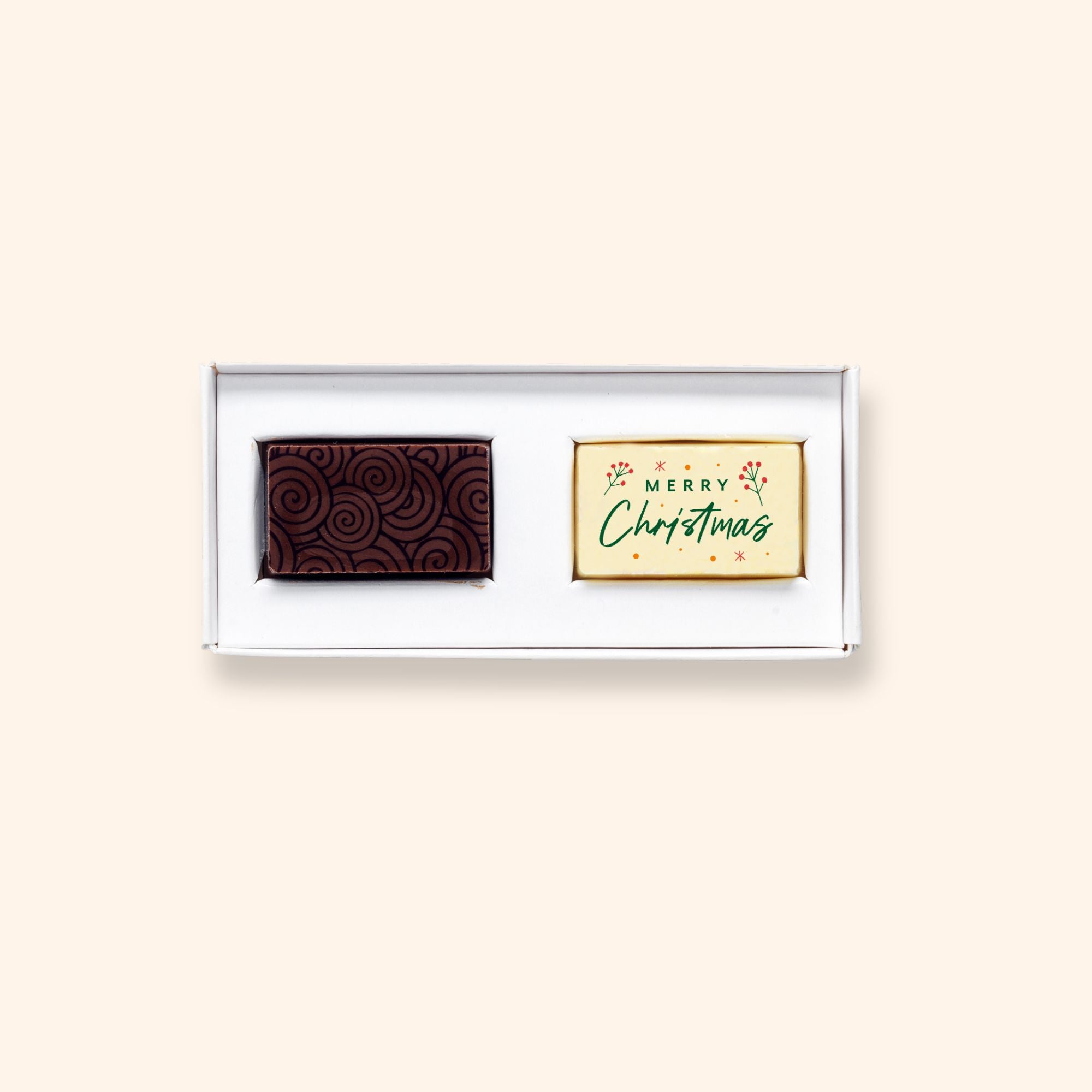 Two hand-crafted chocolates made by Harry Specters shown in 100% recyclable cardboard packaging. The chocolates included in the box are a milk sea salt caramel and a white chocolate with a printed Merry Christmas message.